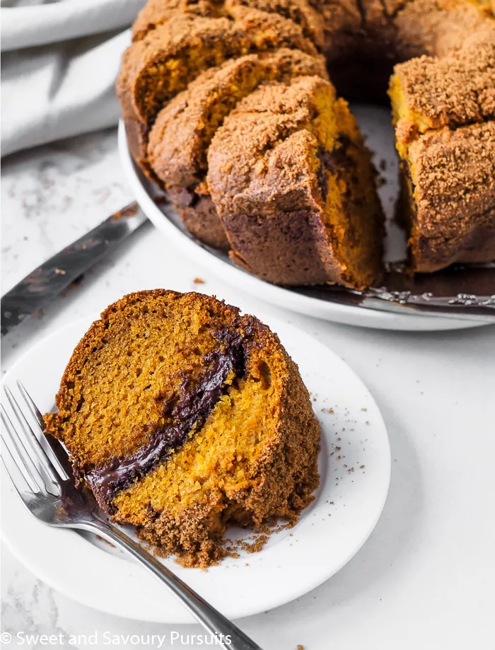 A plated slice of pumpkin cake with a chocolate swirl in the middle of the cake.