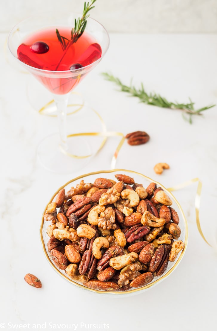 Bowl of spiced walnuts. almonds, cashews and pecan served with a cocktail.