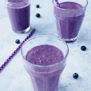 Blueberry Oatmeal Smoothie flavoured with coconut, cinnamon and nutmeg served in glasses.