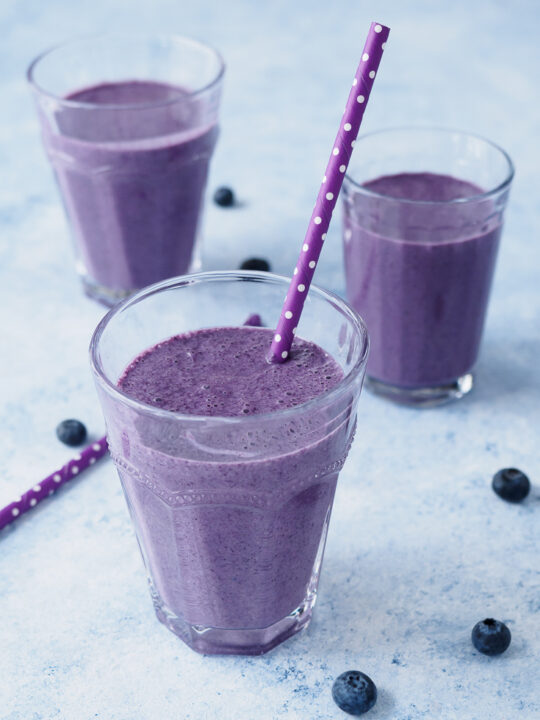 Blueberry Oatmeal Smoothie flavoured with coconut, cinnamon and nutmeg served in glasses.