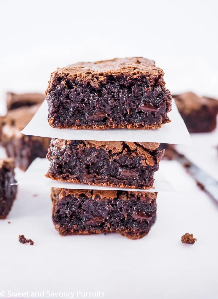 Three gooey gluten-free almond flour brownies piled on top of each other.