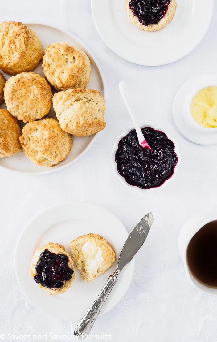 Plate of Irish scones served with butter, mixed berry jam and a cup of tea.