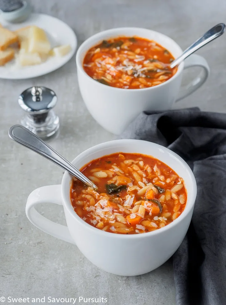 Tomato Orzo Soup served in large white mugs.