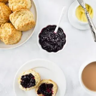 A dish of Irish Scones served with tea, butter and mixed berry jam.