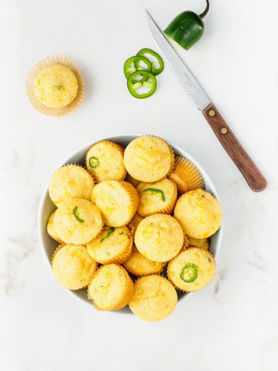 Freshly baked Mini Cornbread Muffins with corn kernels and jalapeno in bowl.