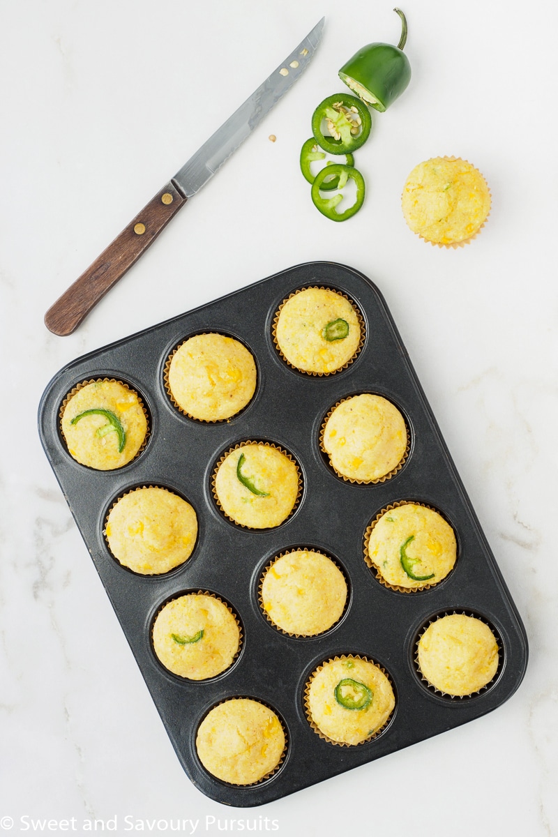 Freshly baked Mini Cornbread Muffins still in the muffin tin with corn and jalapeno.