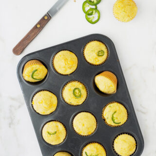 Freshly baked Mini Cornbread Muffins with corn kernels and jalapeño still in muffin tin.