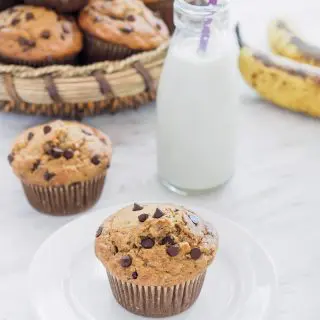 A basket of Banana Oatmeal Chocolate Chip Muffins and one muffin on small dish served with milk.