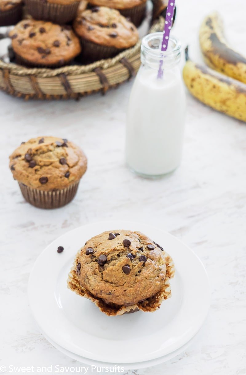 Banana Oatmeal Chocolate Chip Muffin on small white dish served with small bottle of milk.