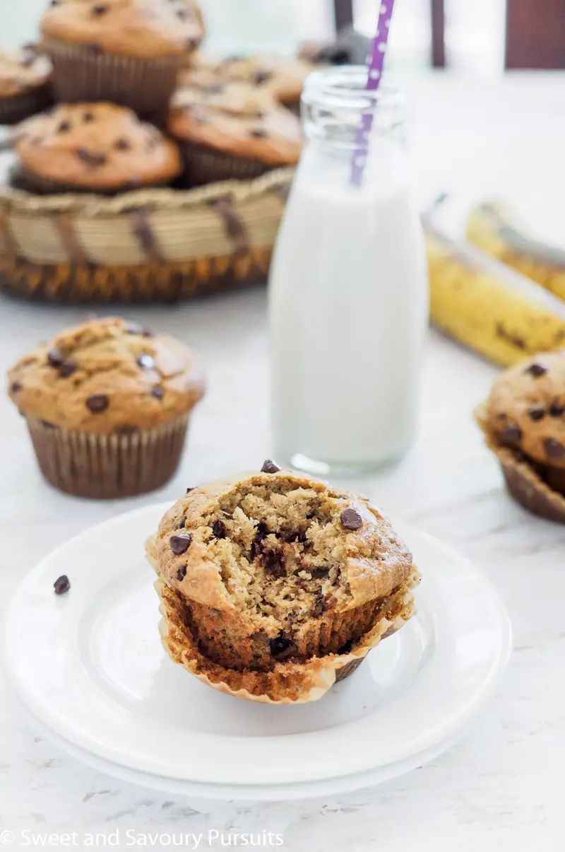 Partially eaten banana aatmeal chocolate chip muffin with more muffins in the background.