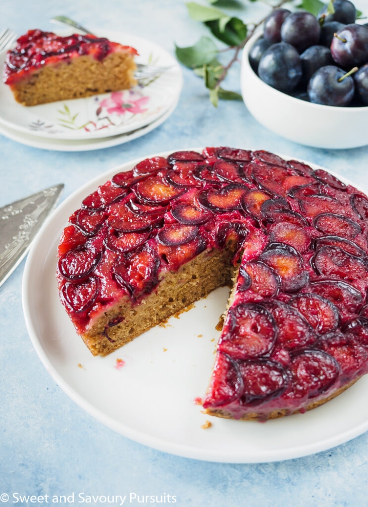 Plum Upside-Down Cake on white dish with slice removed to the side.