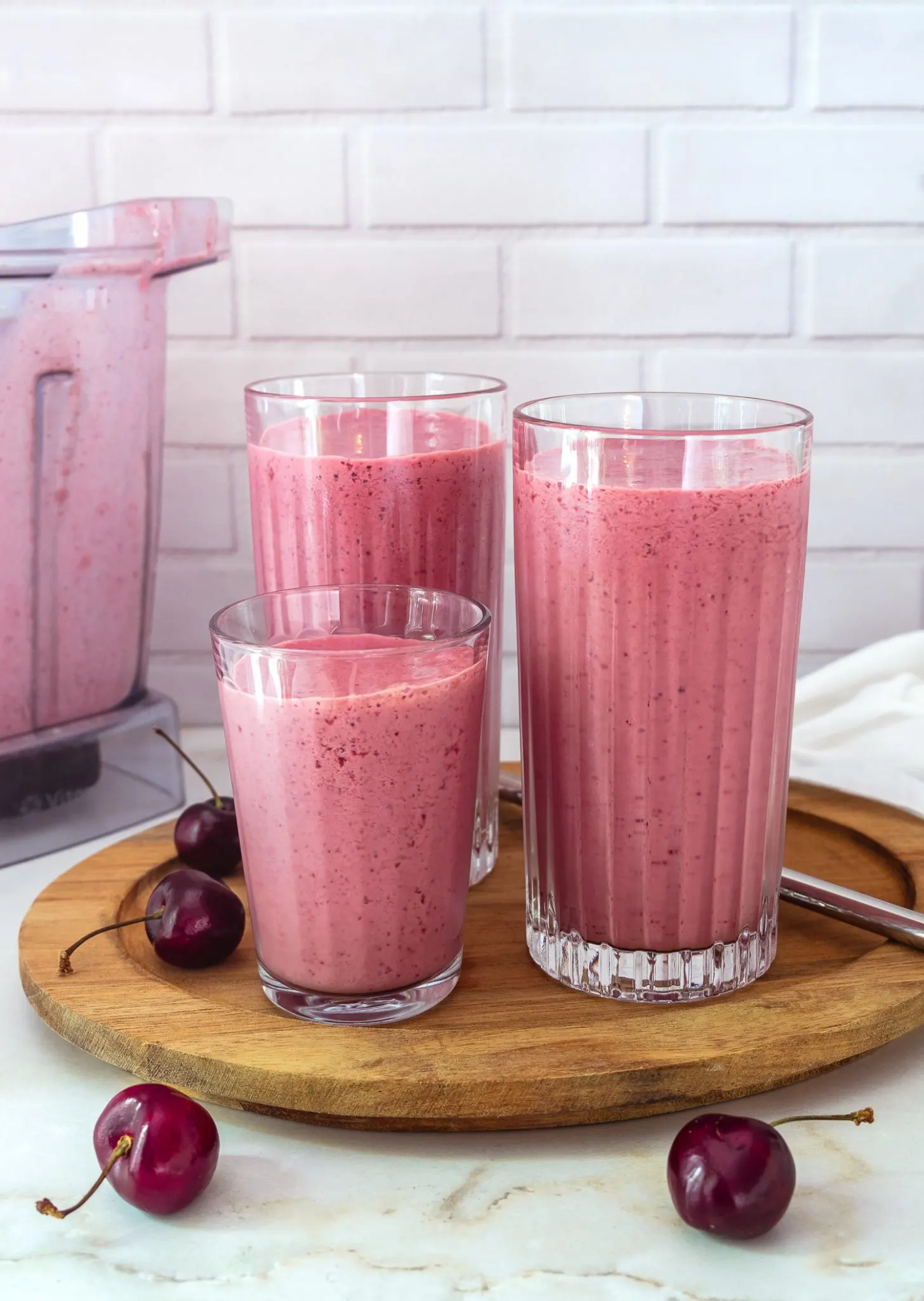 Cherry smoothie served in two tall glasses and a shorter one.