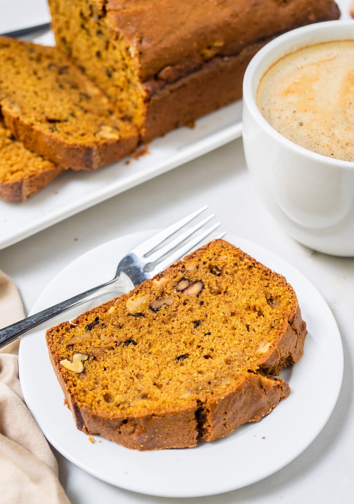 A slice of pumpkin bread on small white dish. 