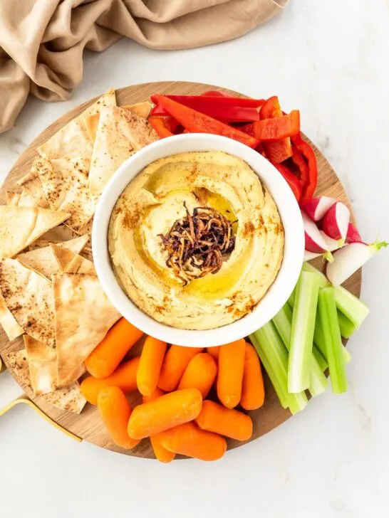 Platter of Caramelized Onion Hummus served with vegetable and pita chips.