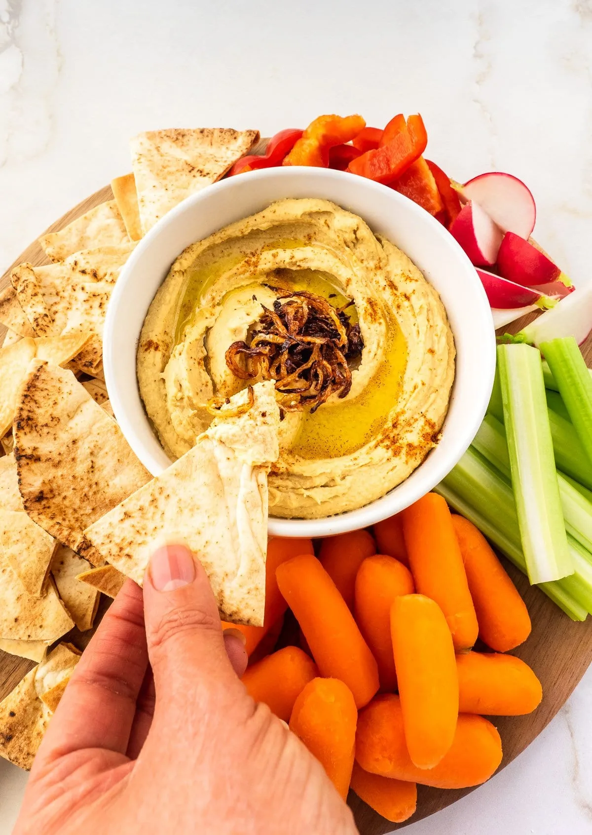 Dish of hummus served with pita chips and fresh vegetables.