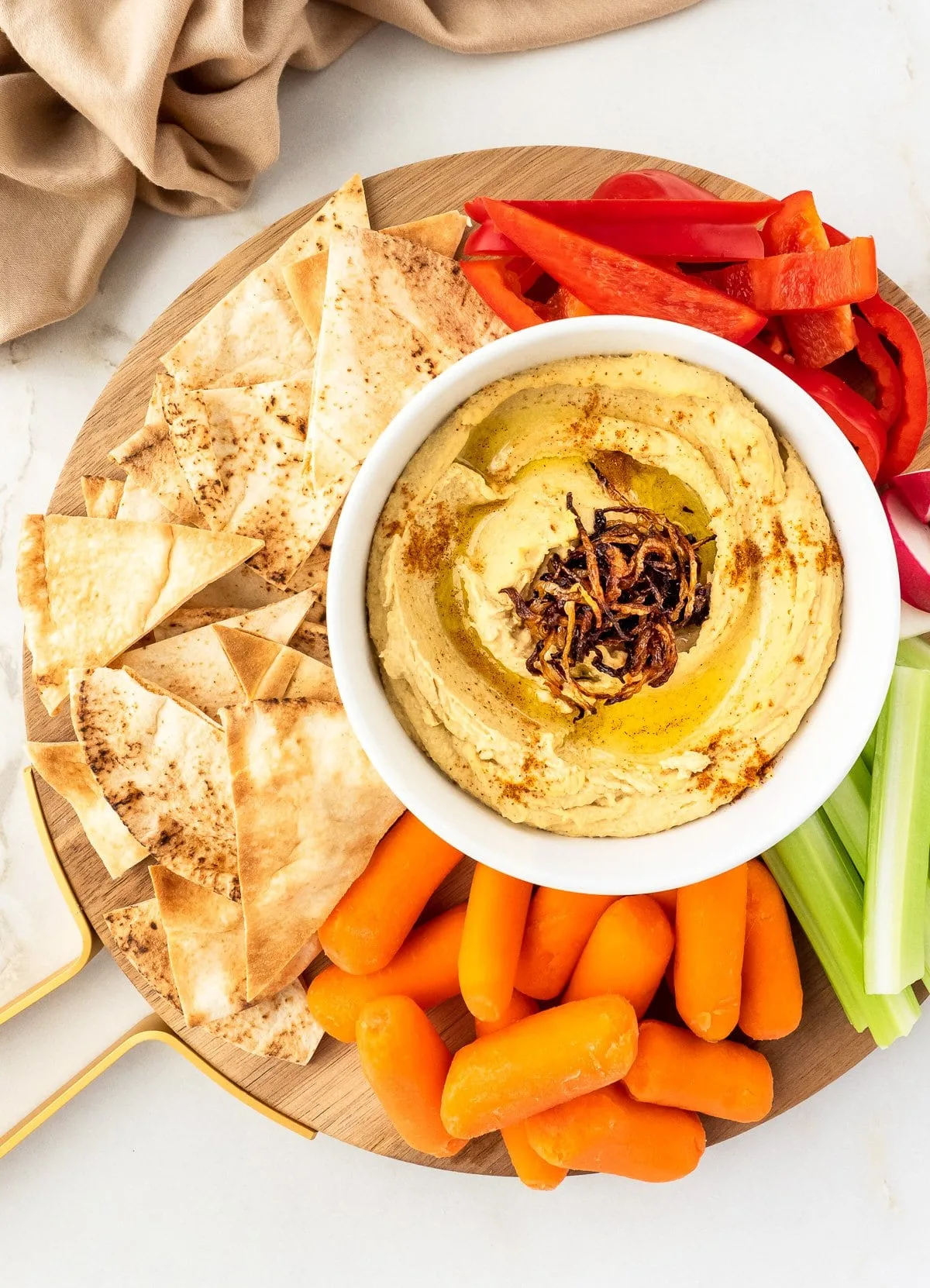 Plate of hummus with pita chips and fresh vegetables.