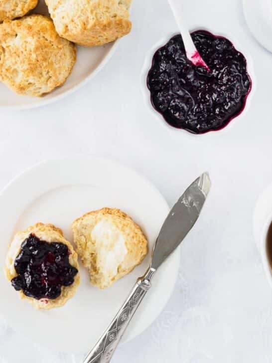 Irish scone topped with butter and berry jam on small dish.