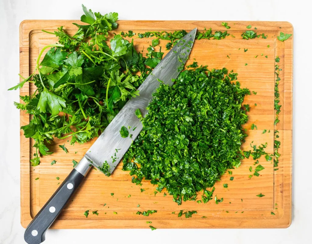 Partially chopped parsley on cutting board.
