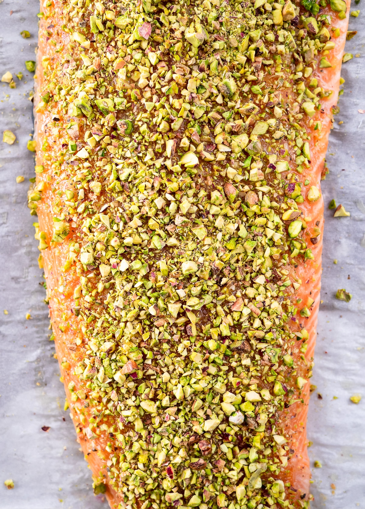 Raw filet of salmon crusted with chopped pistachios.