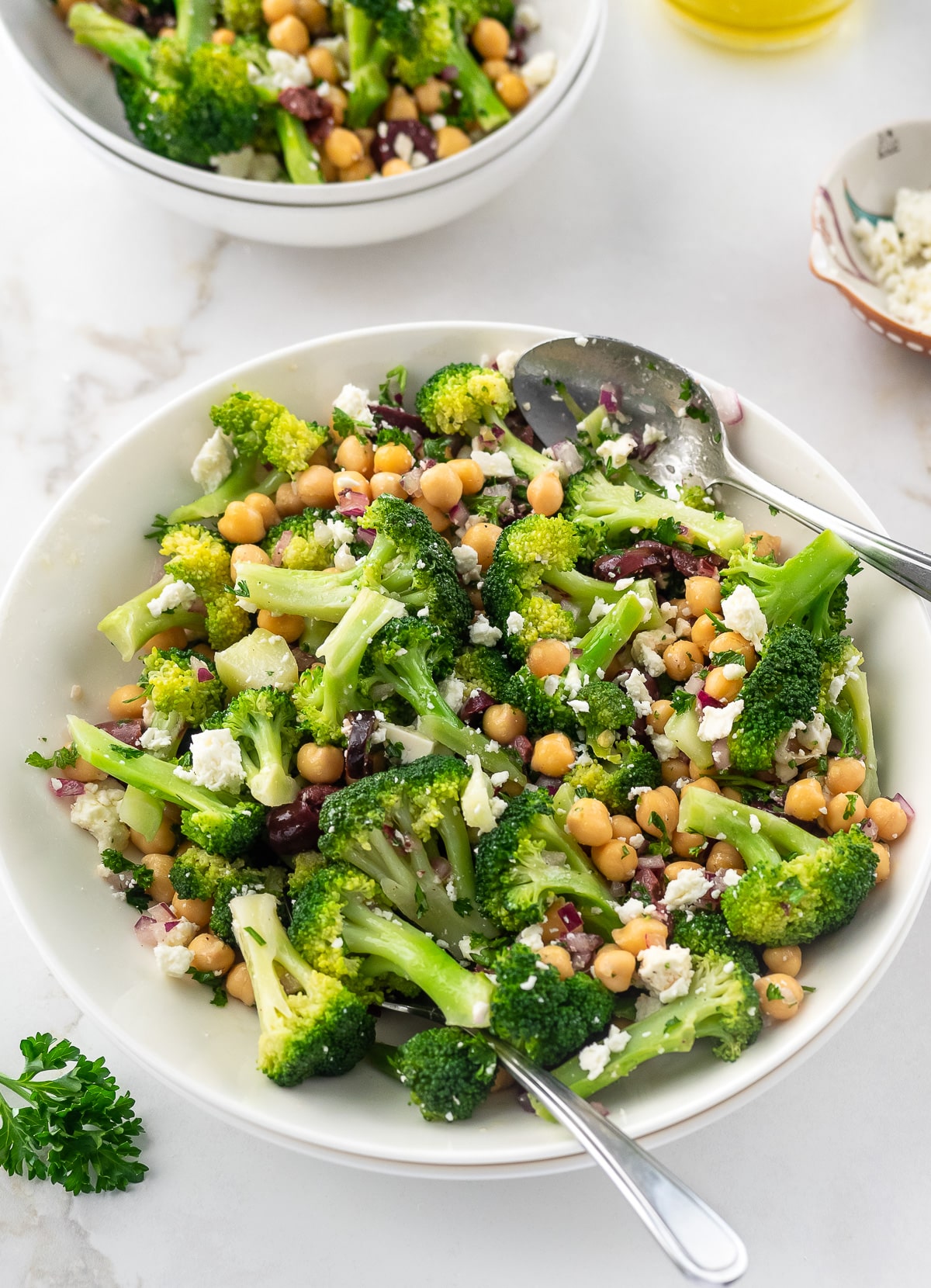 Bowl of chickpea and broccoli salad tossed in lemon and olive oil dressing.
