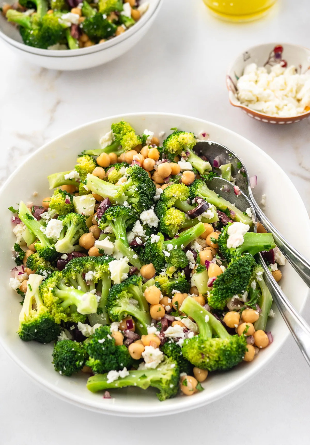 Bowl of chickpea and broccoli salad topped with crumble Feta cheese.