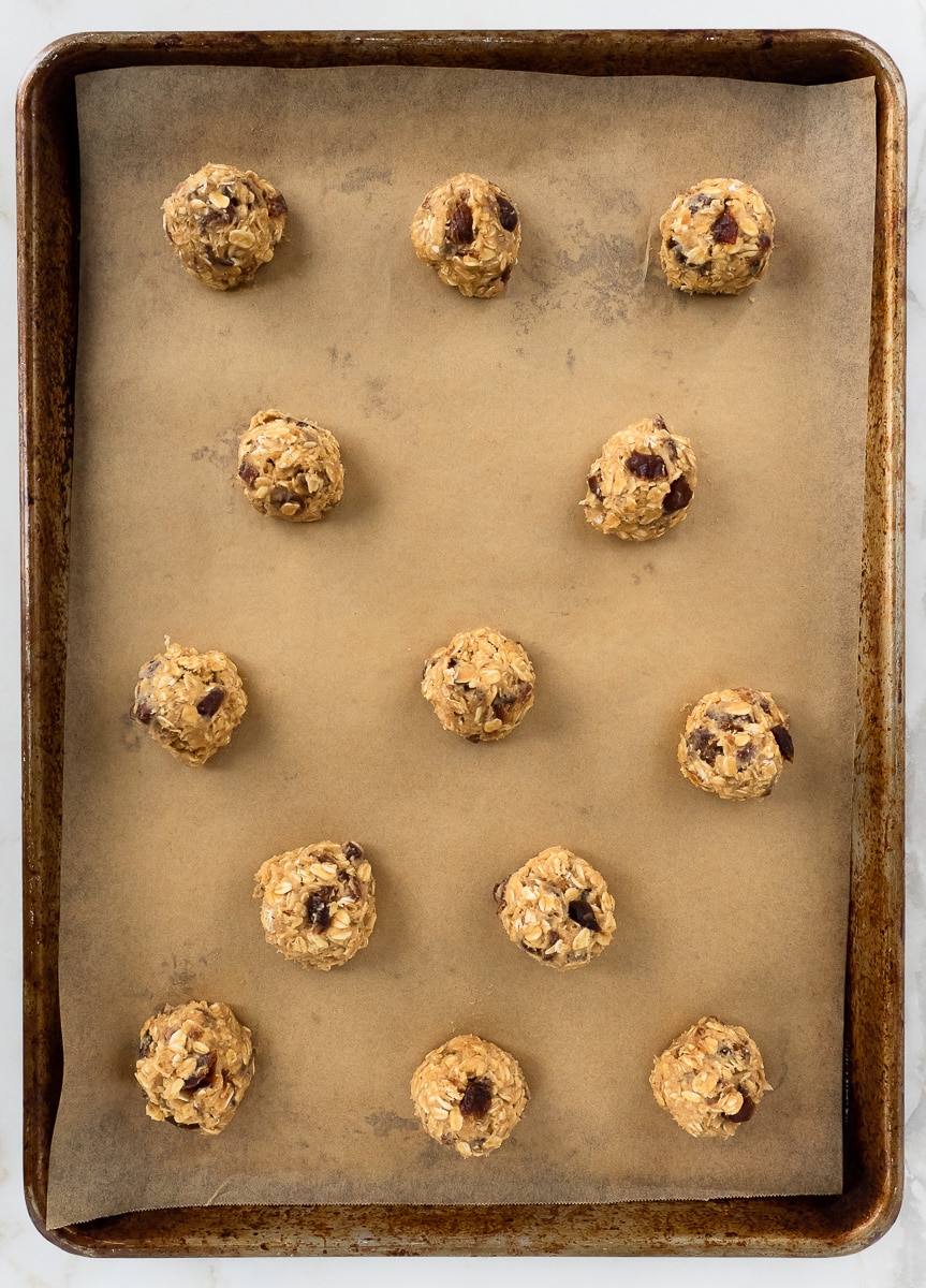 Raw oatmeal cookie dough balls on baking sheet.