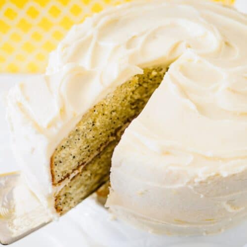 Lemon poppy seed cake with slice being removed.