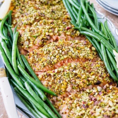 Pistachio crusted salmon on serving platter with green beans on the side.
