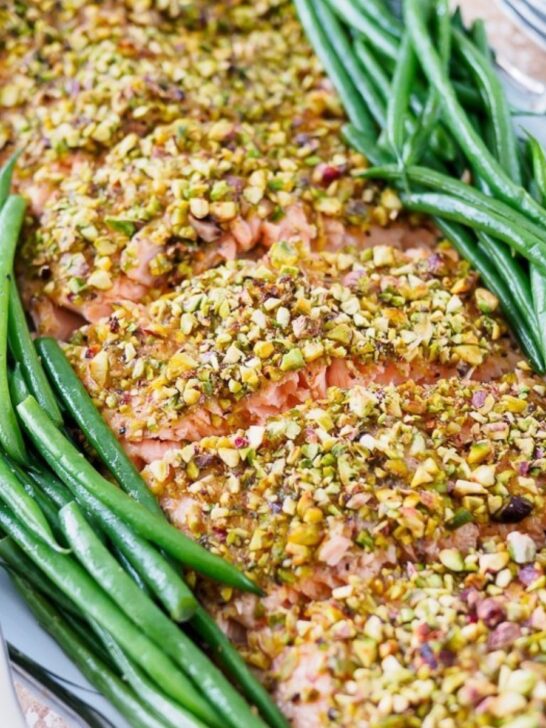 Pistachio crusted salmon on serving platter with green beans on the side.