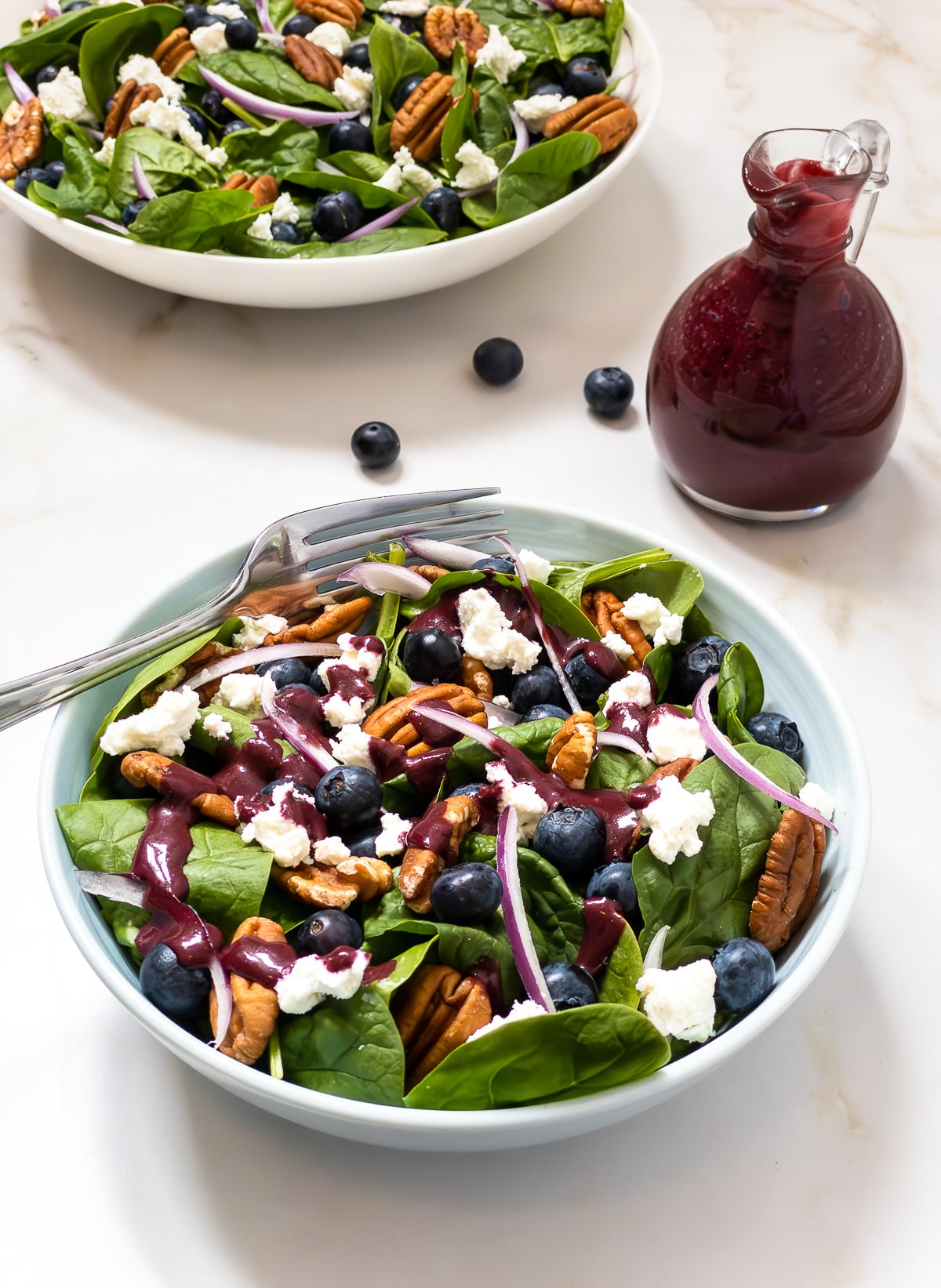 Small bowl of blueberry spinach salad topped with blueberry balsamic vinaigrette.