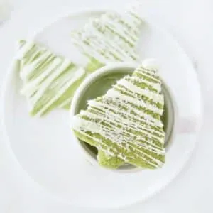 Matcha sugar cookies on plate with a cup of matcha latte.