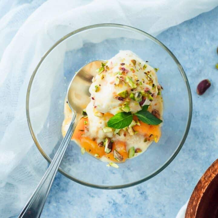 Bowl of ice cream topped with peach sauce.