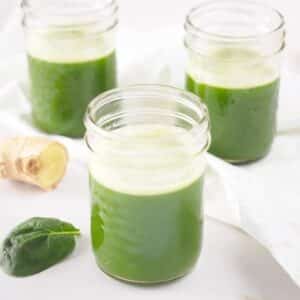 Pineapple spinach juice with ginger served in small mason jars.