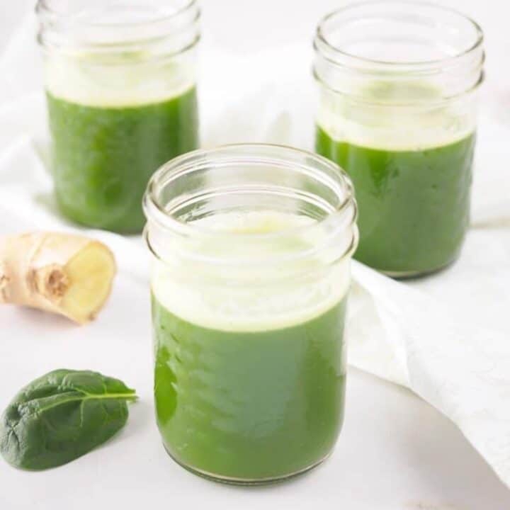 Pineapple spinach juice with ginger served in small mason jars.