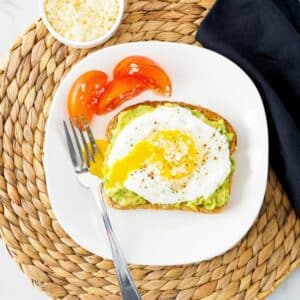 Plate of avocado toast topped with fried egg.