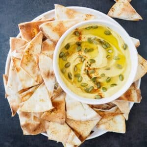 Bowl of butternut squash and white bean dip served with pita chips.