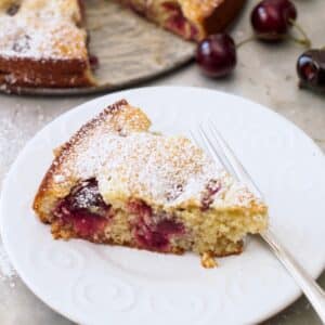 Slice of cherry almond cake on small plate.