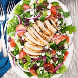 Greek salad with grilled chicken on plate.