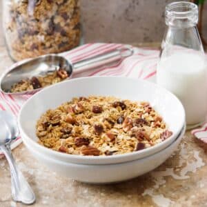 Bowl of maple pecan granola with a bottle of milk on the side.