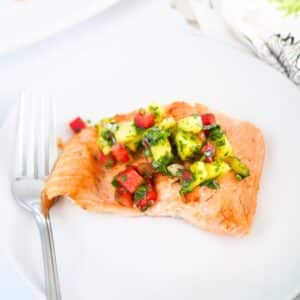Pan fried rainbow trout topped with pineapple salsa on dish.