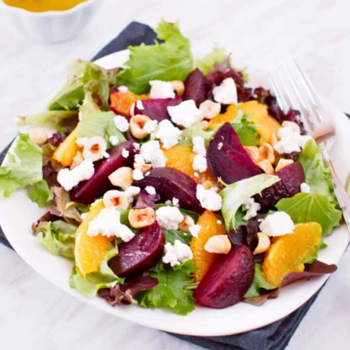 Plate of roasted beet and orange salad served with citrus vinaigrette.