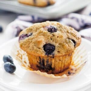 Blueberry muffin on small white dish.
