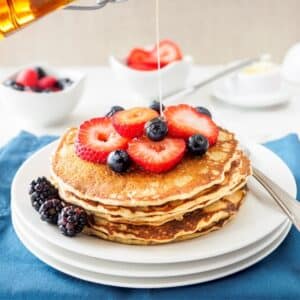 Stack of whole wheat quinoa flour pancakes topped with berries.