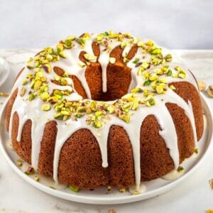 Pistachio bunt cake topped with glaze and chopped pistachios.