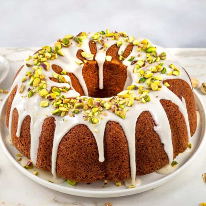 Pistachio bunt cake topped with glaze and chopped pistachios.