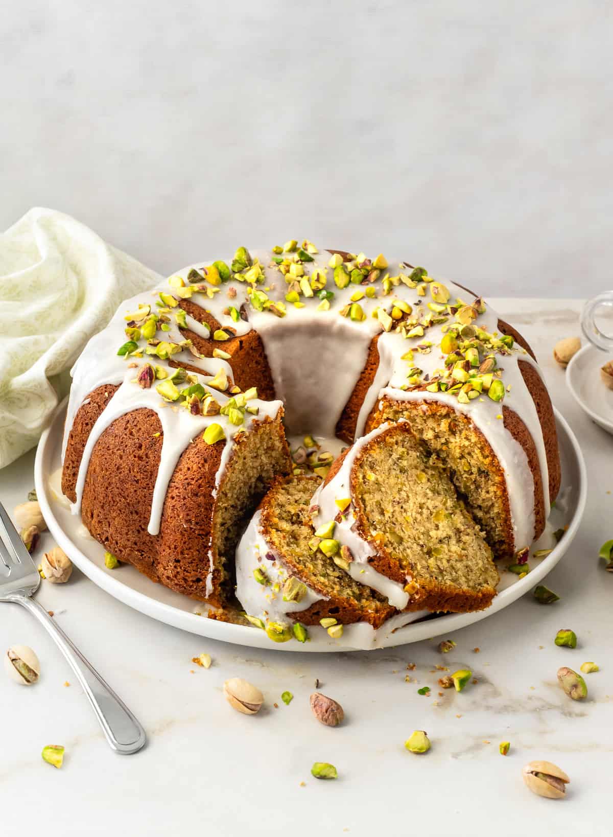 Pistachio bundt cake with two slices cut on platter.