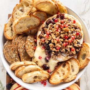 Serving platter with a Baked Brie, crostini and fruit.