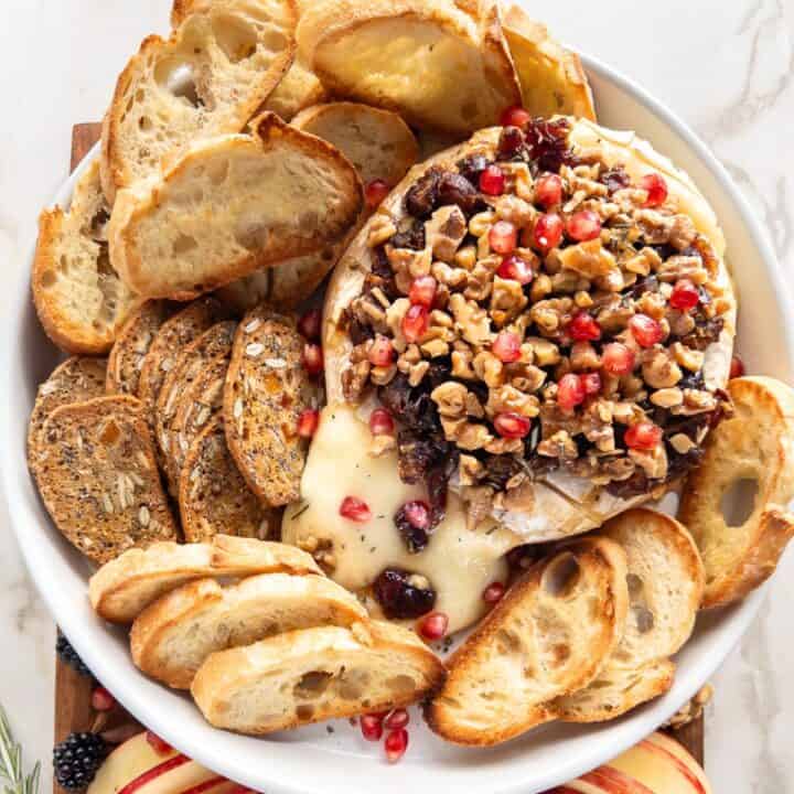Serving platter with a Baked Brie, crostini and fruit.